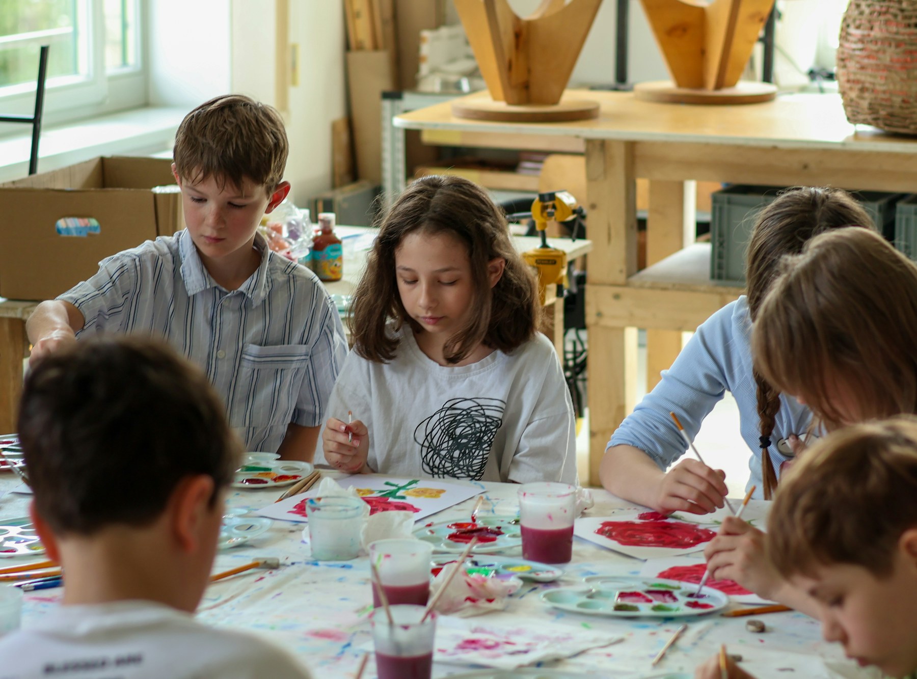 Students paint together around a classroom table.