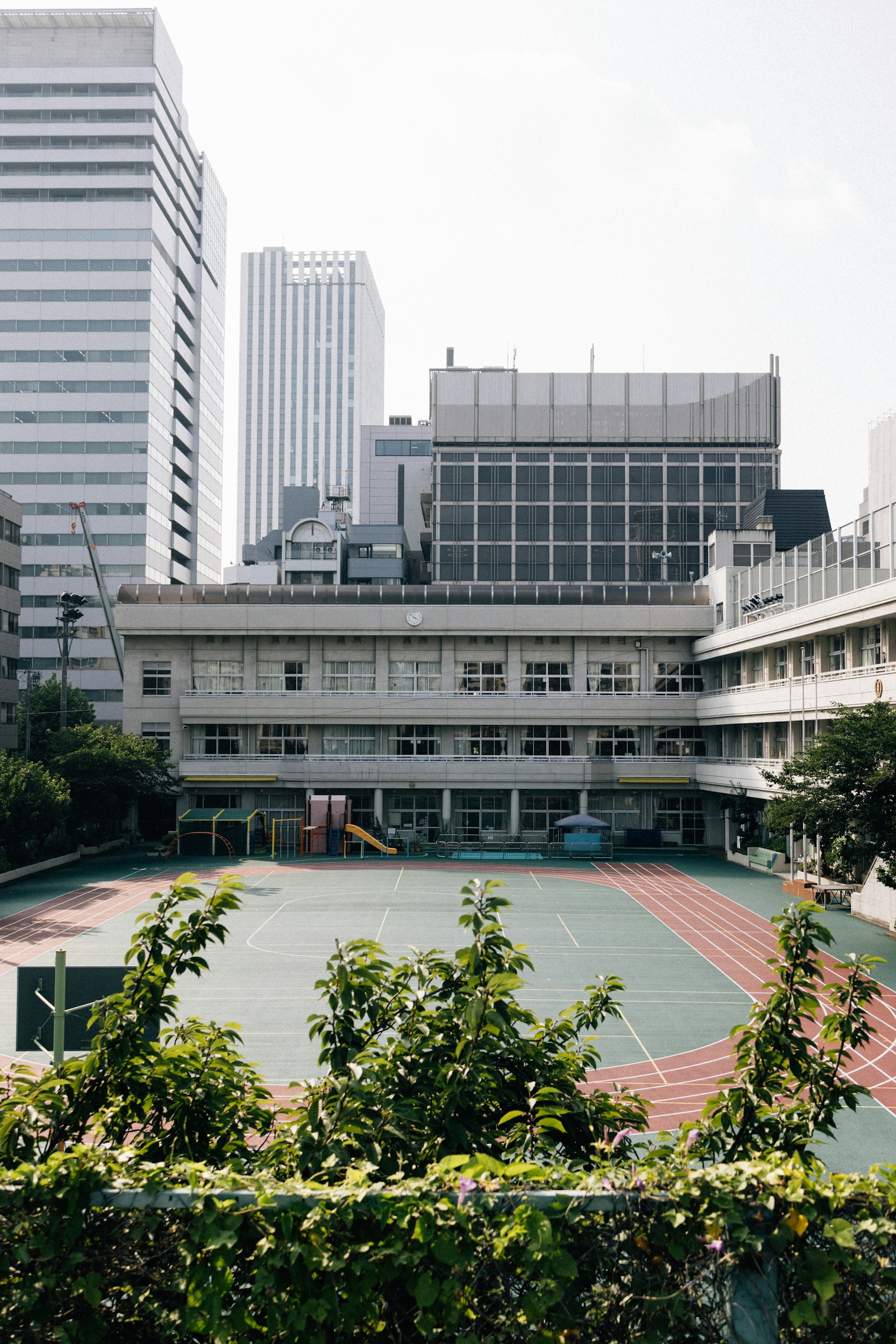 A schoolyard with an outdoor court and surrounding buildings.